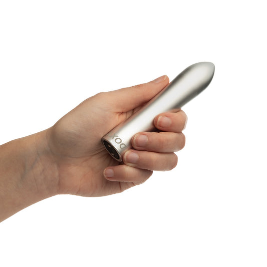 Doxy Silver Bullet vibrator held in hand, showcasing its sleek metallic design and compact shape.